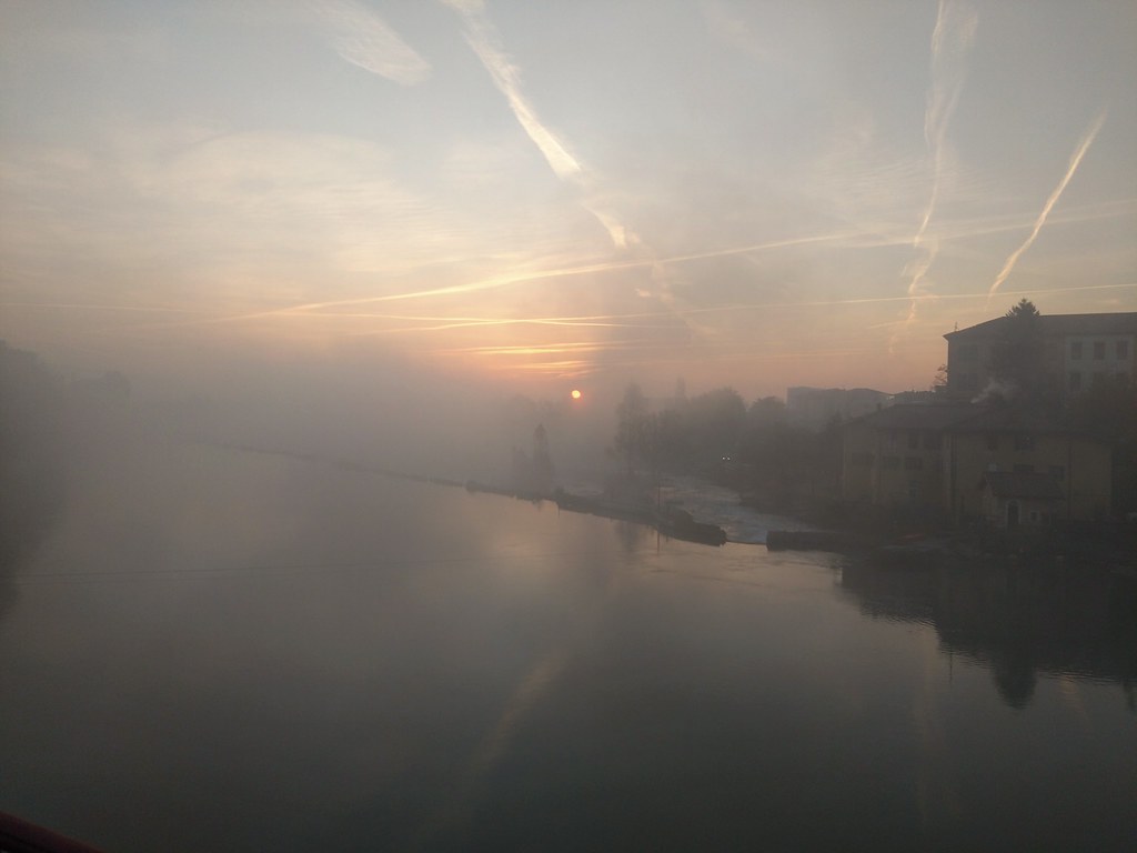 sun is rising over ivrea and its river